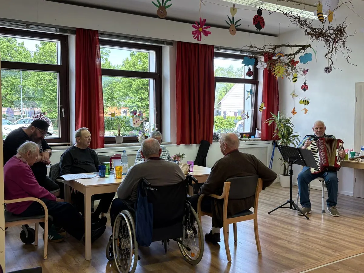 Gäste der Tagespflege hören einem Alleinunterhalter mit Akkordeon zu