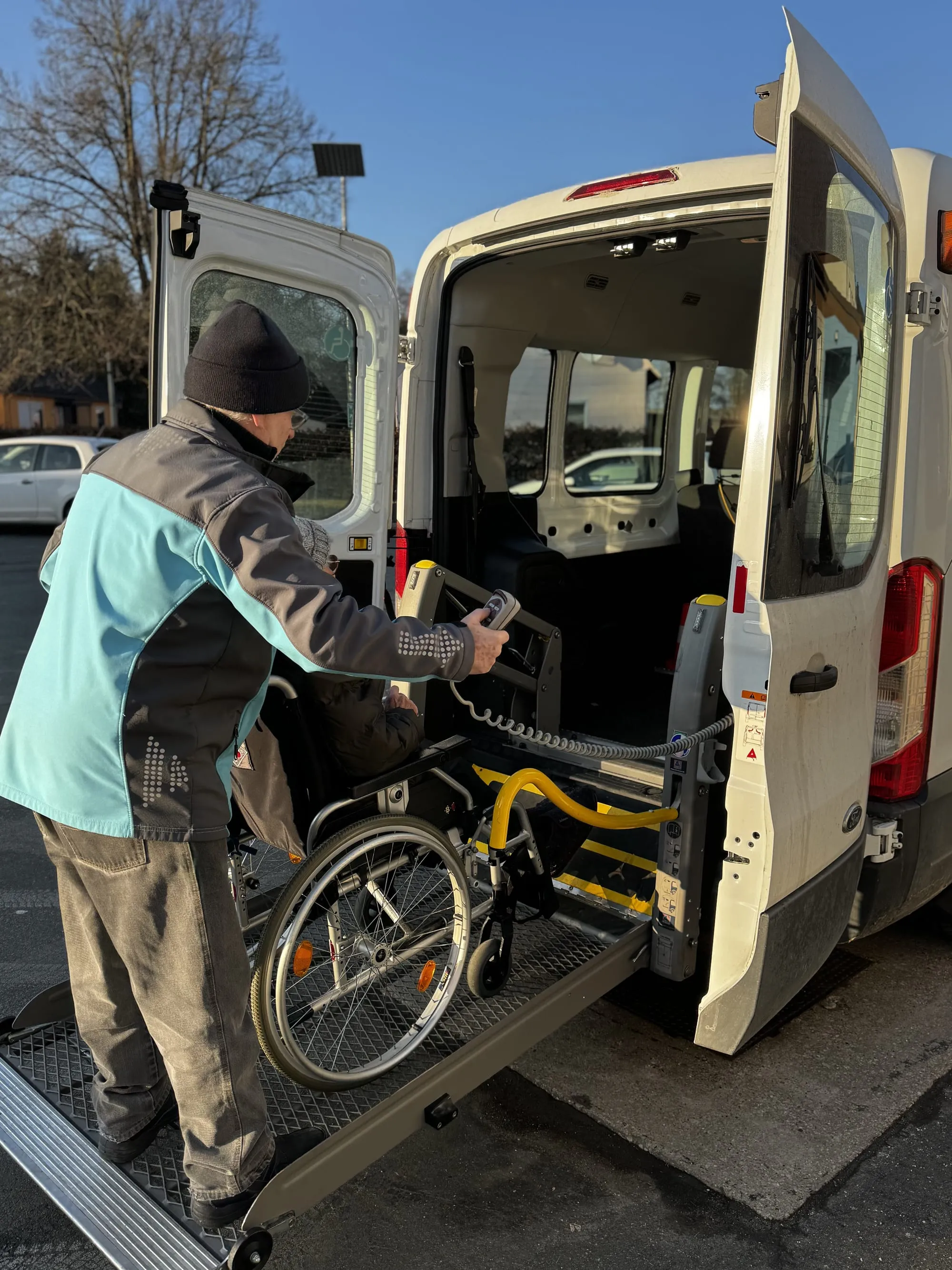 Ein Rollstuhl wird über die Hebebühne in den Kleinbus gefahren