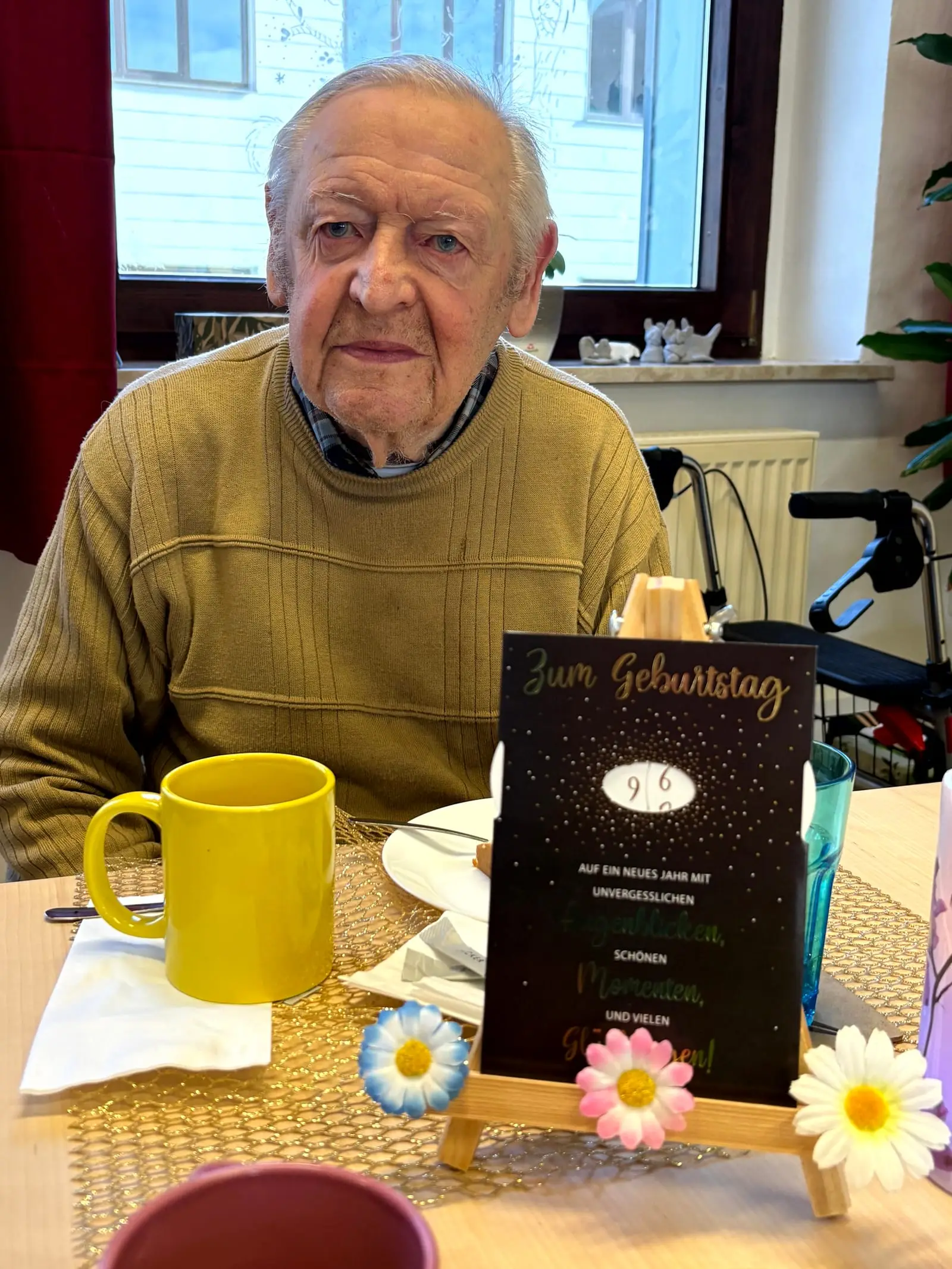 Ein Gast sitzt an seinem Geburtstag vor einer Glückwunschkarte am gedeckten Tisch