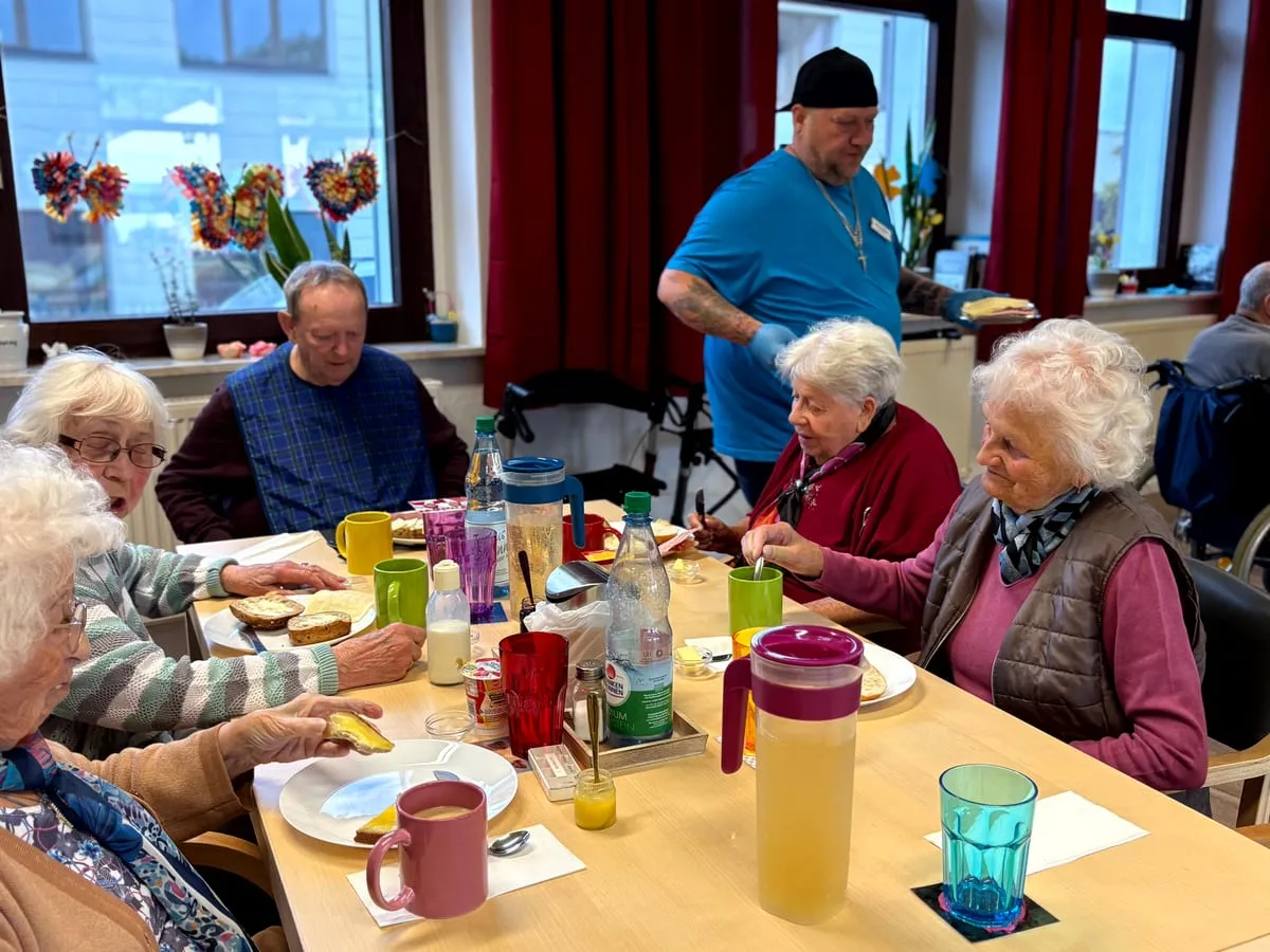 Gäste und ein Betreuer beim gemeinsamen Mittagessen am gedeckten Tisch
