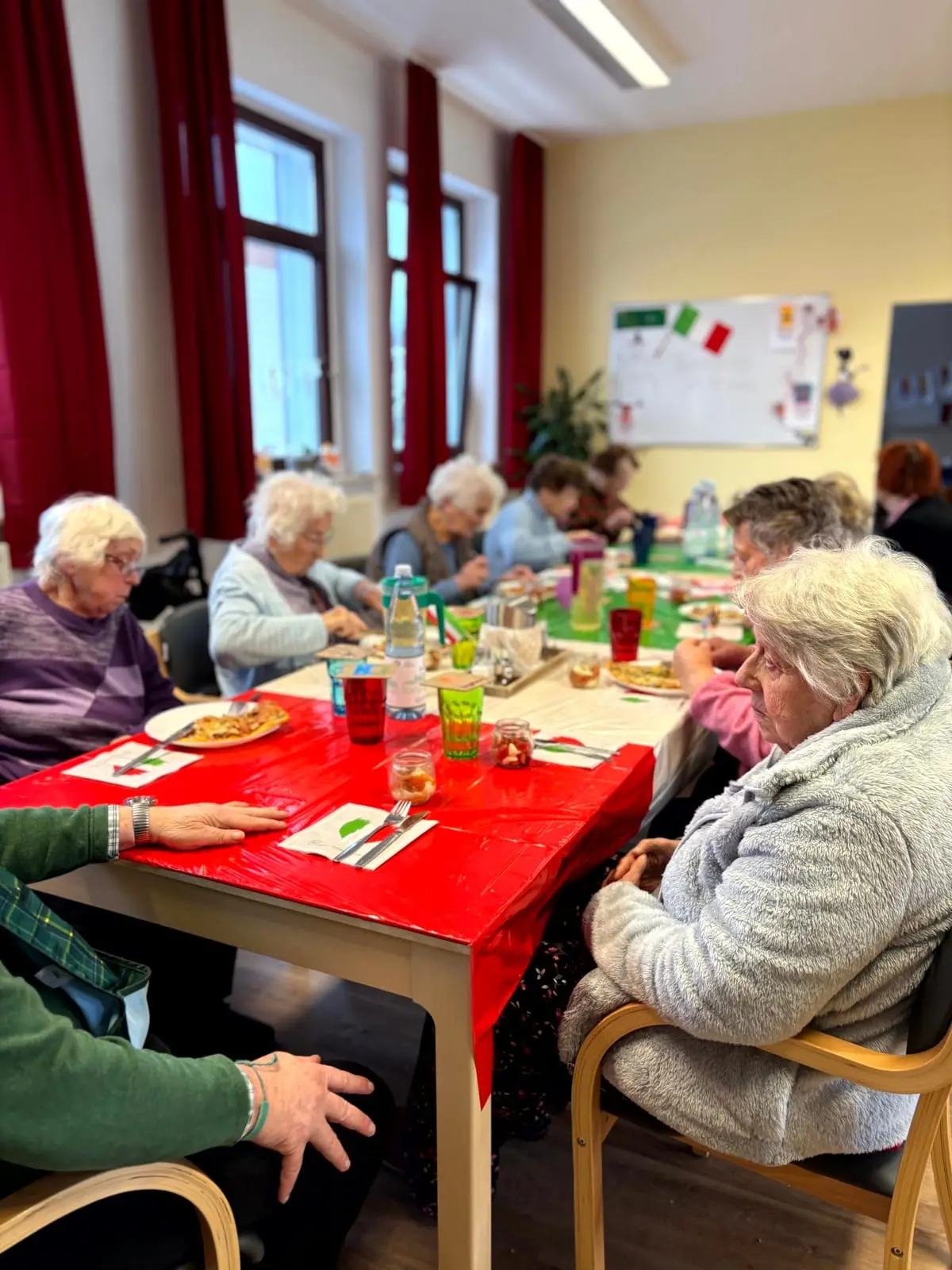 Gäste sitzen am rot gedeckten Tisch beim gemeinsamen Mittagessen