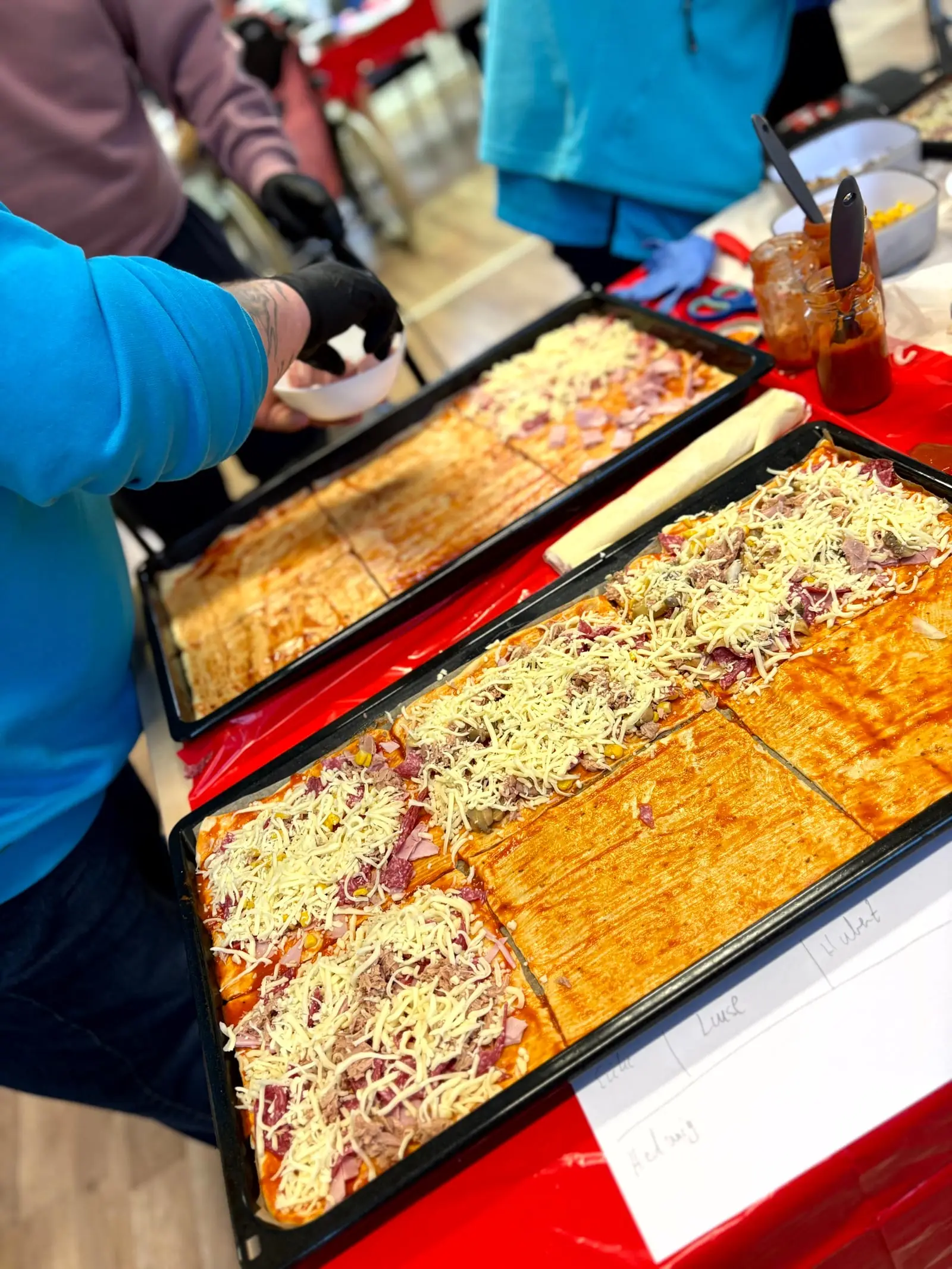 Frisch belegte Pizzableche werden aus dem Ofen genommen