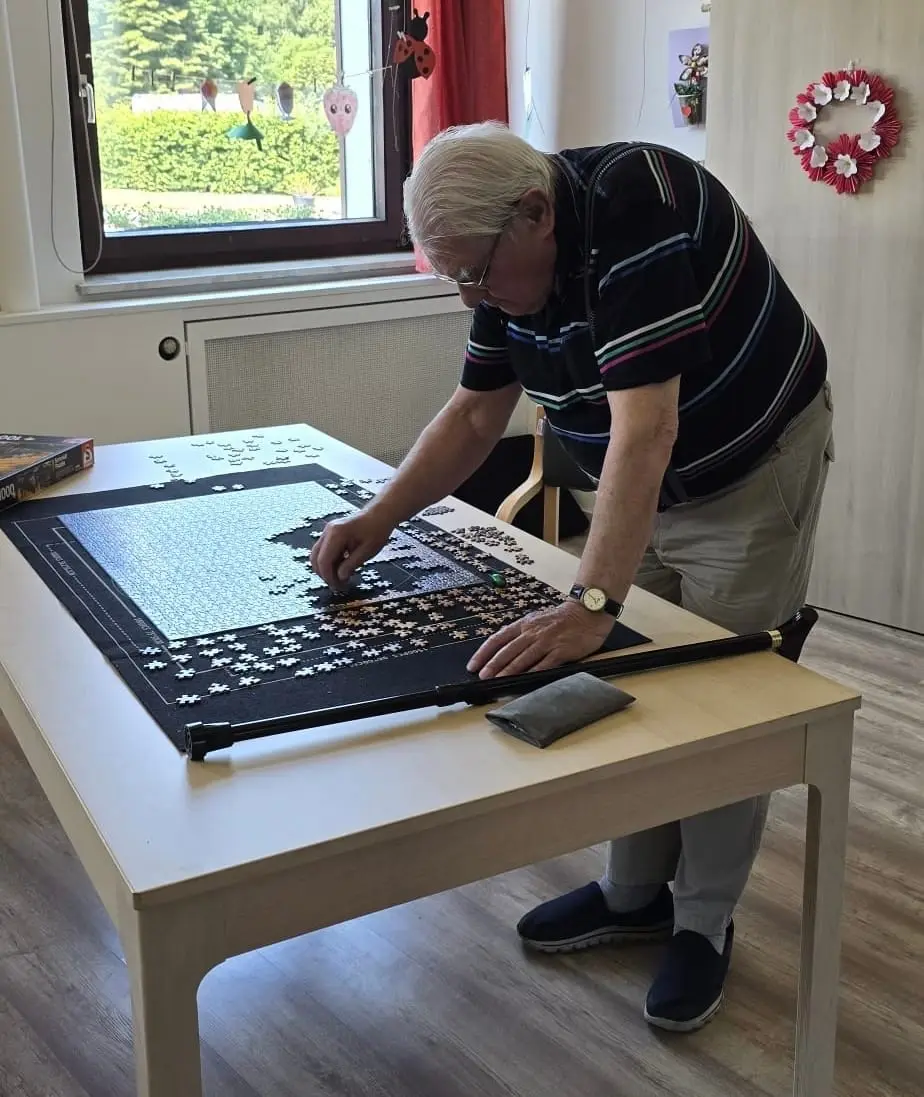 Ein Gast legt konzentriert an einem großen Puzzle am Fenster