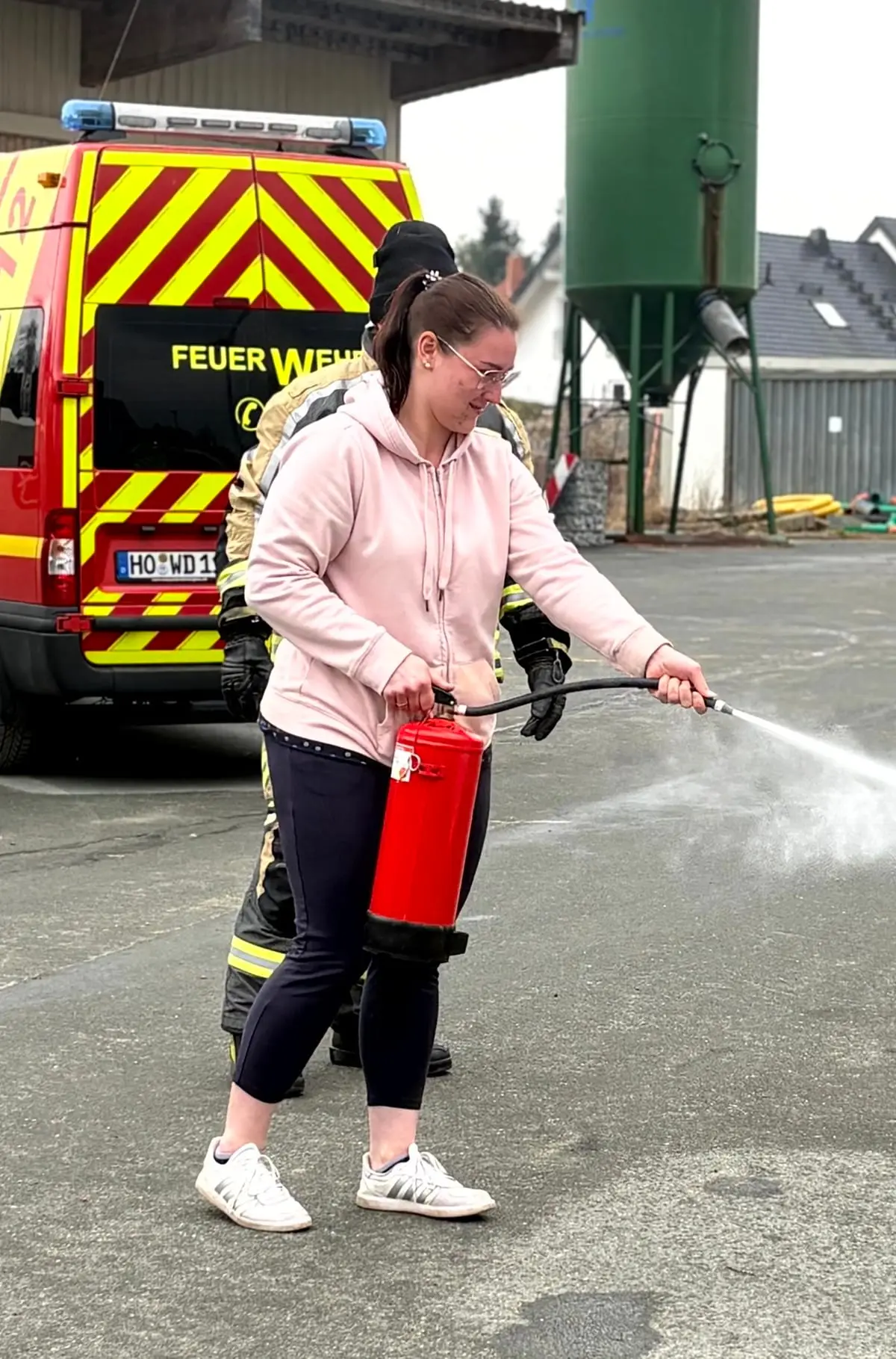 Eine Mitarbeiterin löscht unter Anleitung der Feuerwehr ein Übungsfeuer