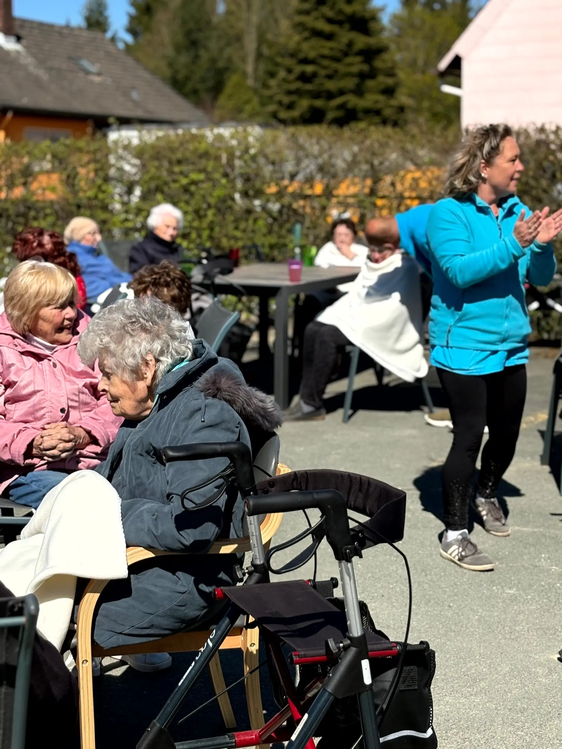 Gäste sitzen beim Sommerfest im Freien und machen bei der Gymnastik mit